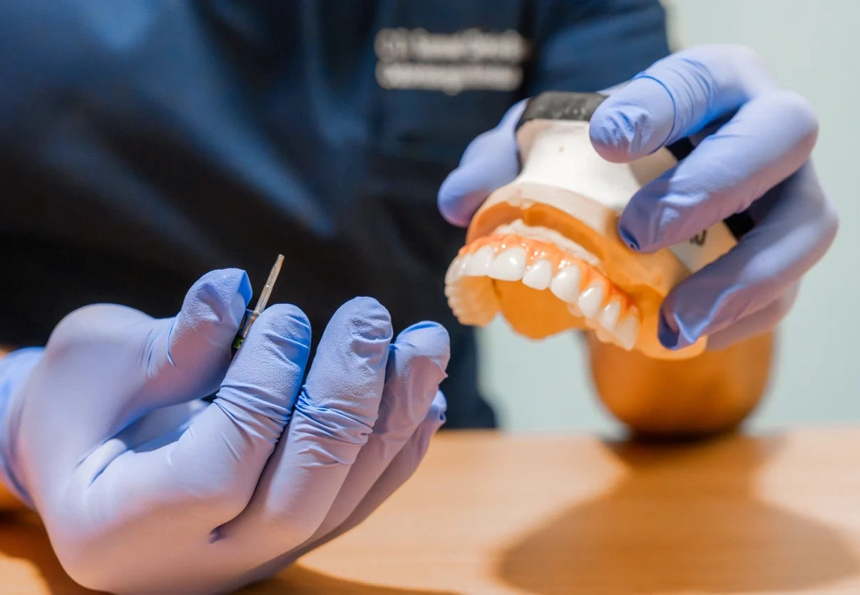 Dentist holding a dental model while reviewing whether All-on-4 is enough for a full arch.