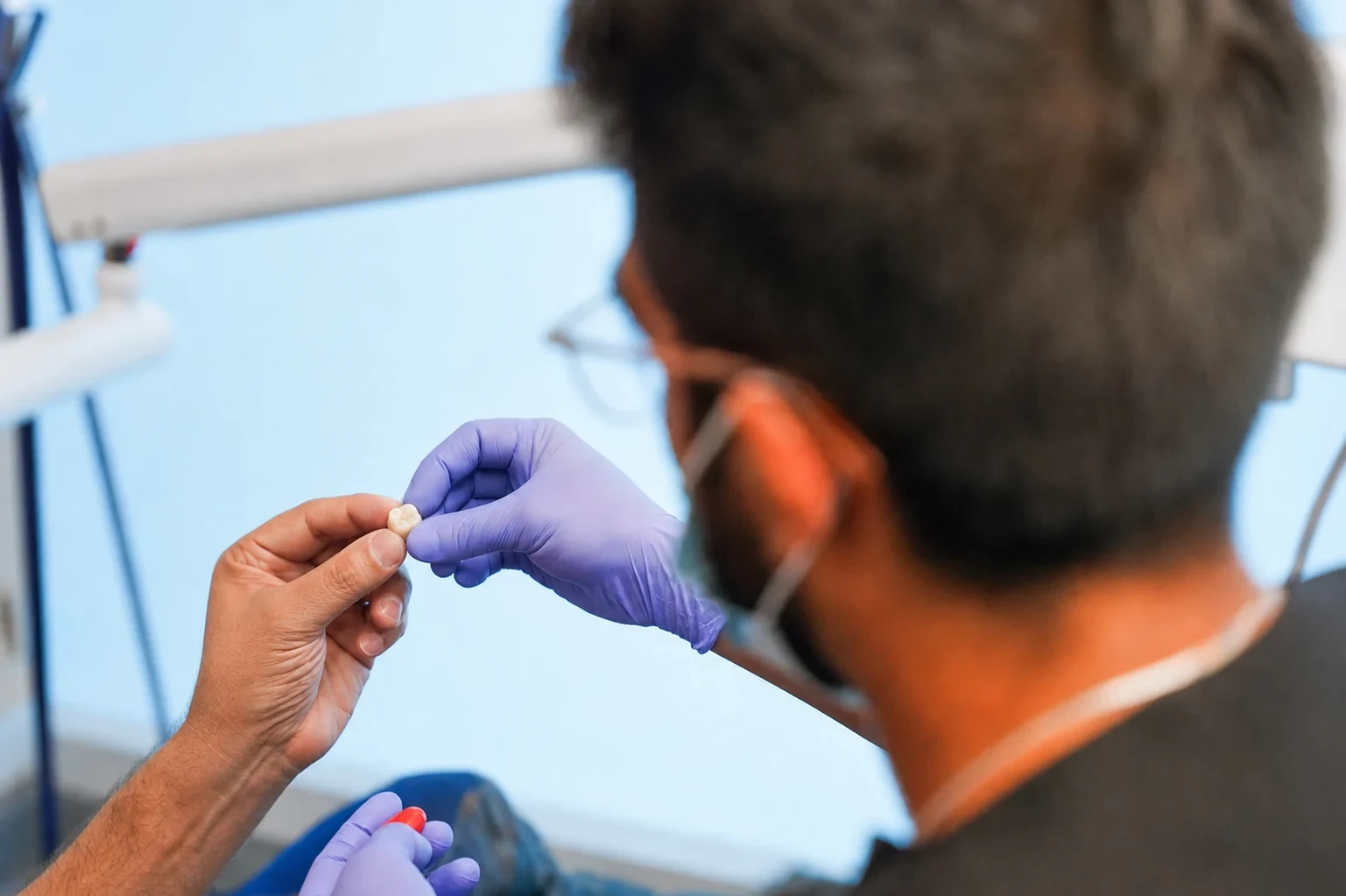 Dentist and patient holding a ceramic dental crown during restorative planning at hisonrisa in Mexico City.