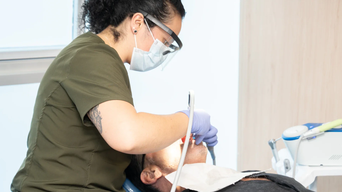 A hisonrisa clinician provides dental care to a patient in the treatment chair.
