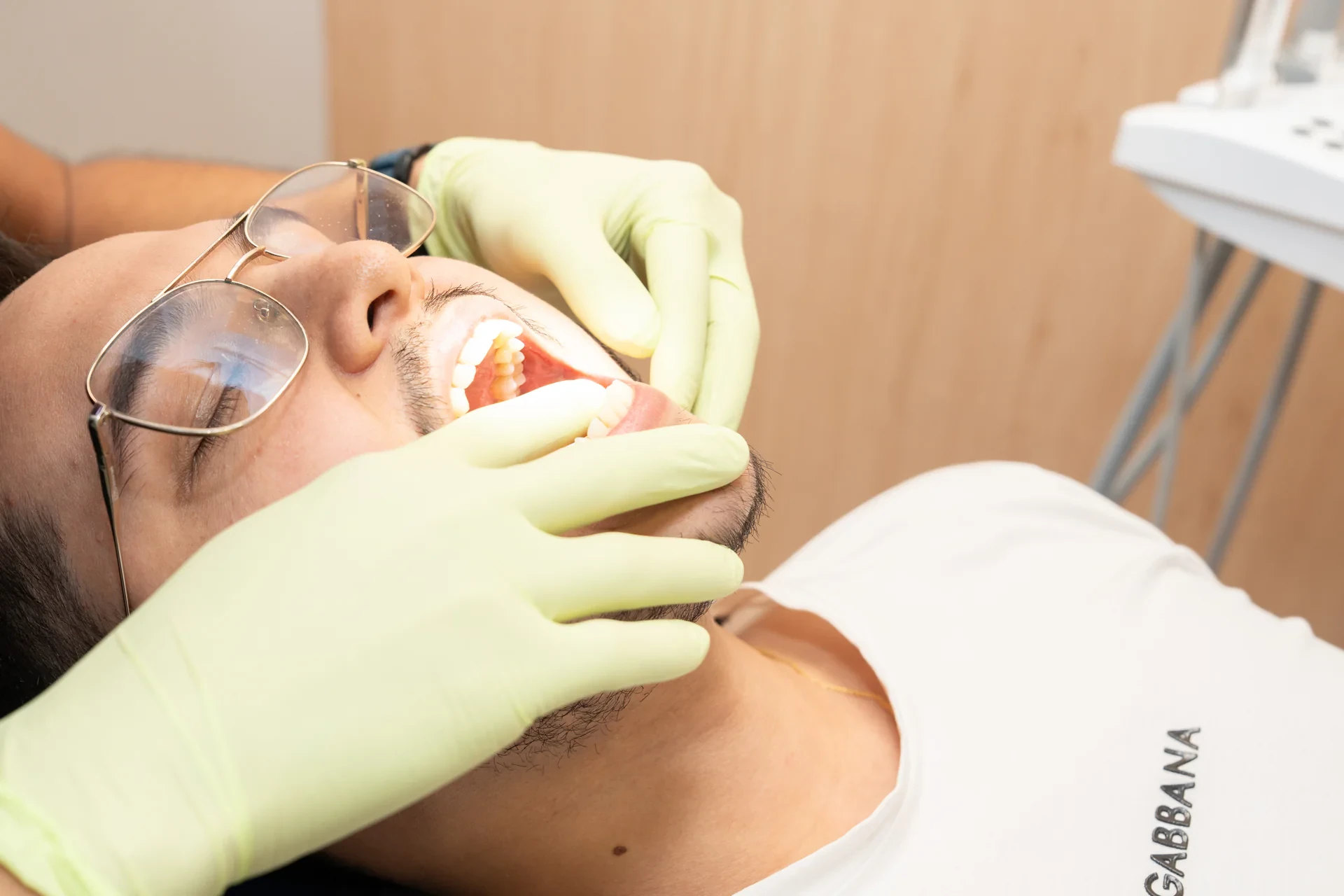 A hisonrisa clinician examines a patient's teeth during an in-person dental evaluation.