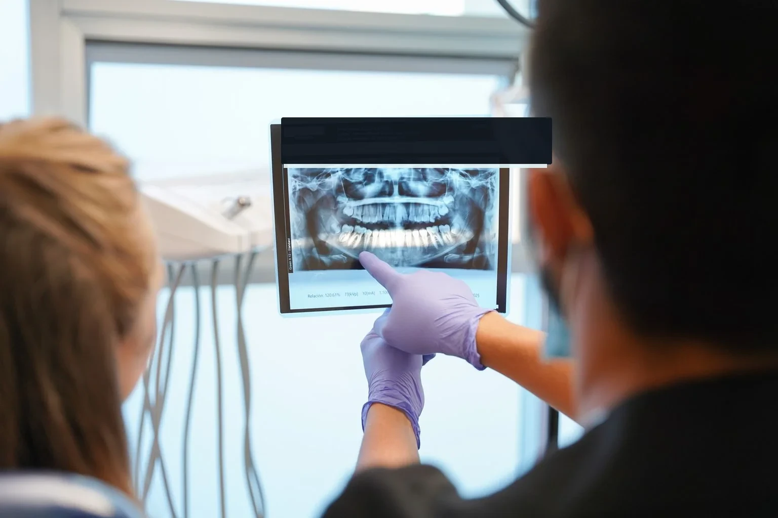 Dentista señalando una radiografía panorámica durante la revisión de una corona dental.