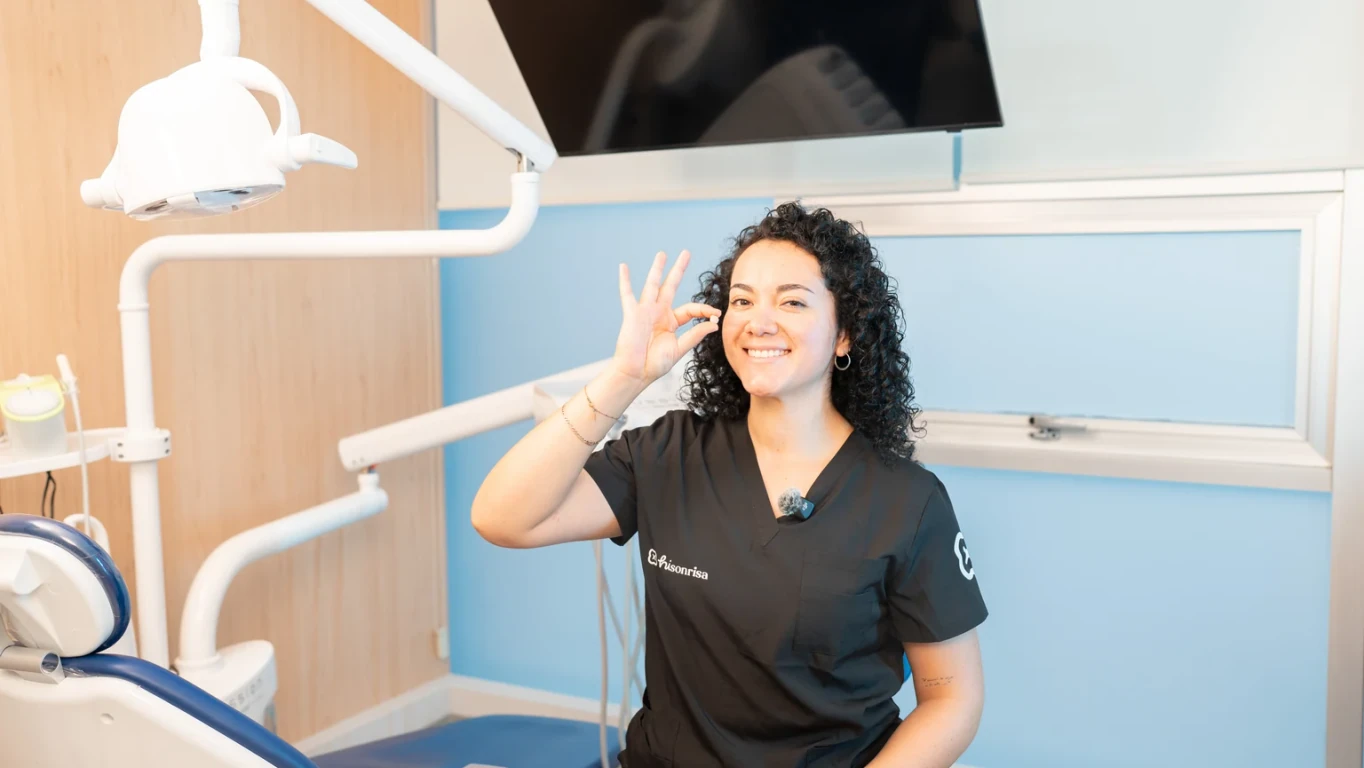 Dentista de hisonrisa sosteniendo una corona dental en un consultorio.