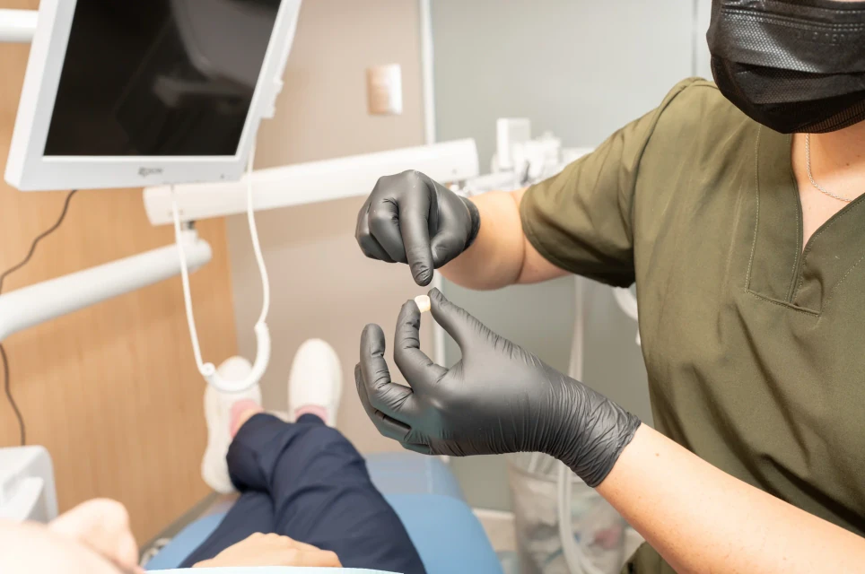 Profesional de hisonrisa sosteniendo una muestra de corona dental durante la planeación del tratamiento.