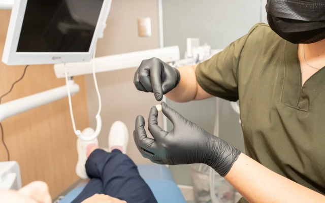 Profesional de hisonrisa sosteniendo una muestra de corona dental durante la planeación del tratamiento.
