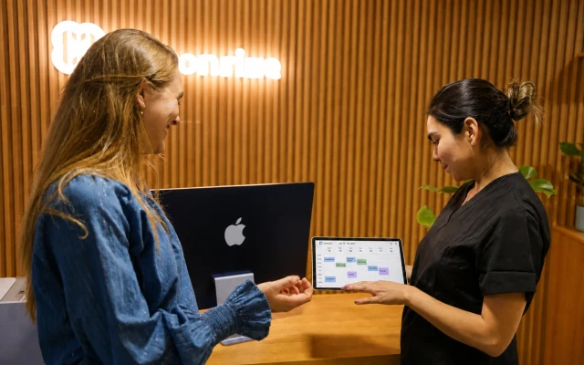 Clinic team member showing a Google Calendar schedule to a patient at hisonrisa in Mexico City.