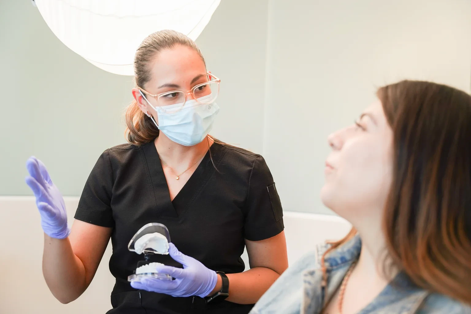 Clinician using a dental model to explain treatment planning during a patient consultation.