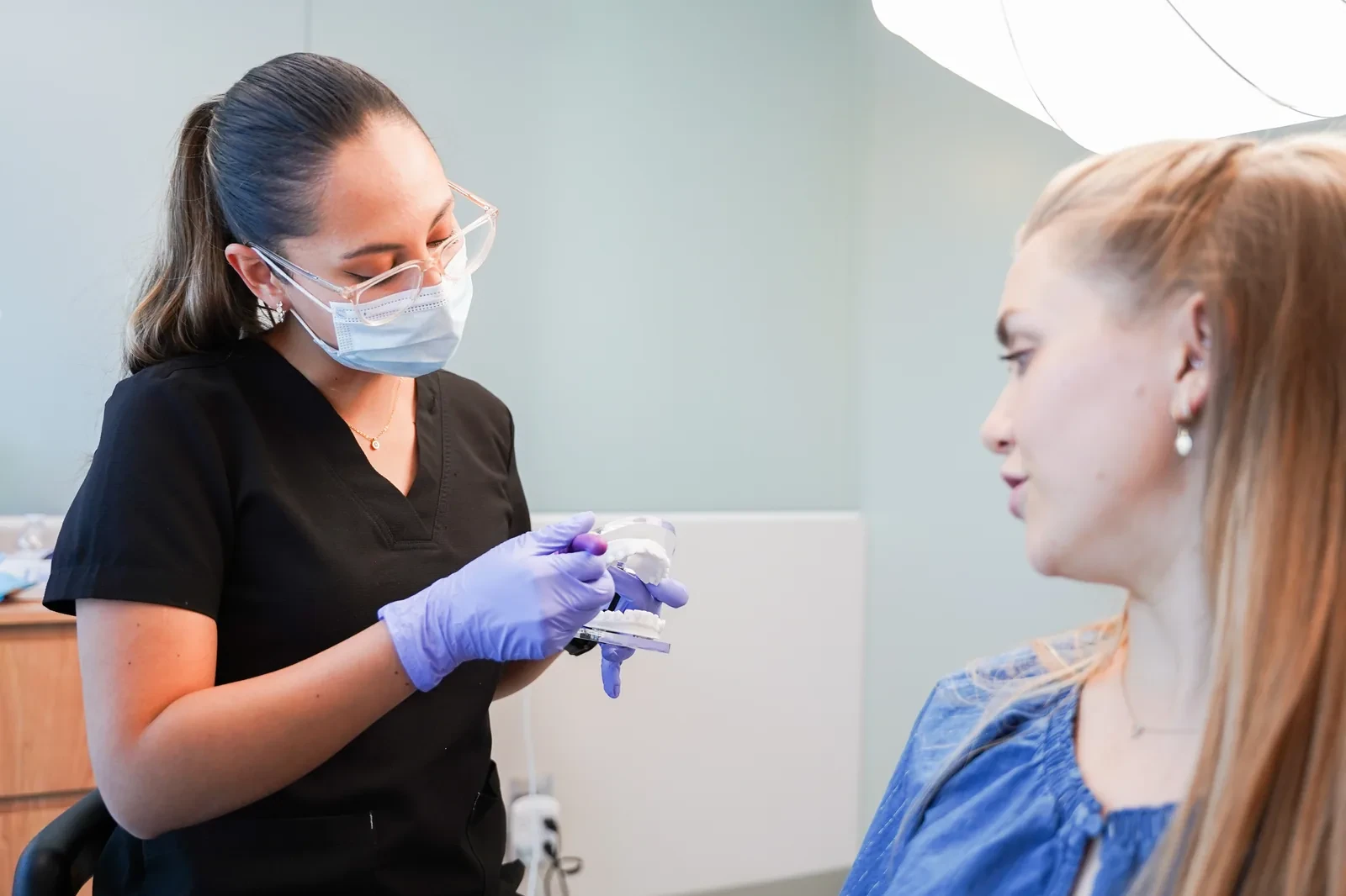 Dentista conversando con una paciente durante la revisión de una muela rota.