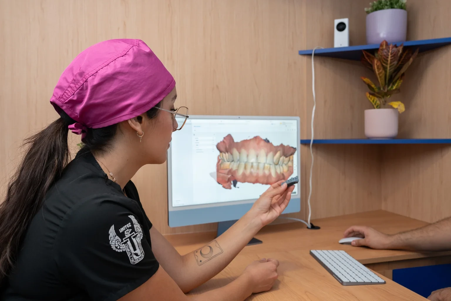 Persona del equipo revisando un modelo dental 3D durante una consulta restaurativa.