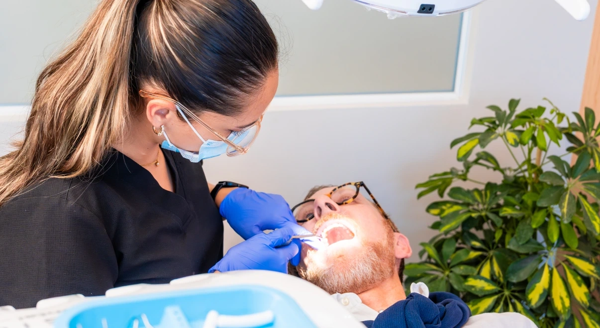 Clinician checking a patient during a periodontal cleaning evaluation at hisonrisa in Roma Sur.