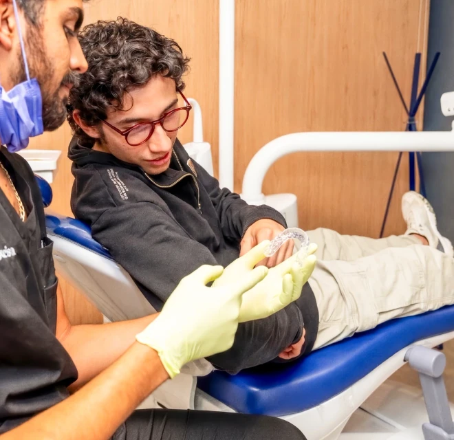 Dentist showing a custom night guard to a patient at hisonrisa in Roma Sur, Mexico City.