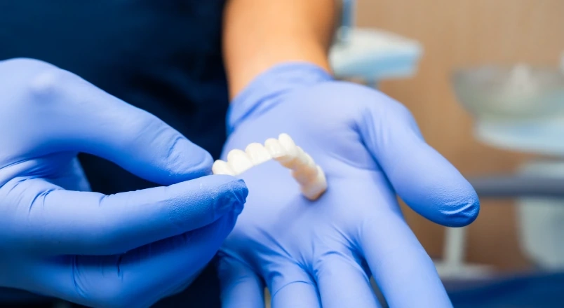 Dentist showing a dental bridge model during an options comparison.