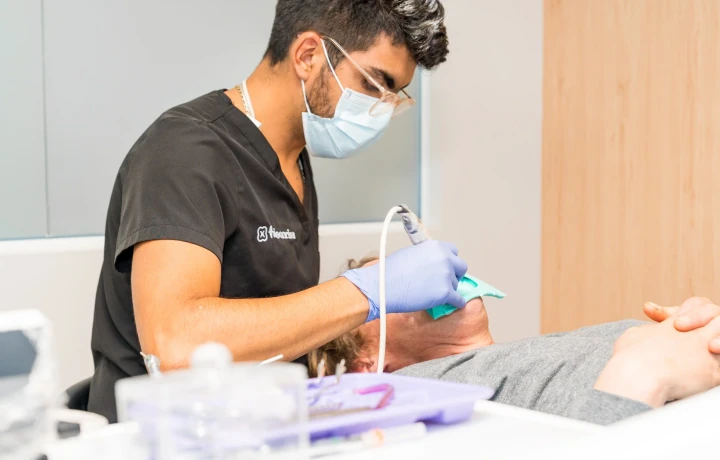 A hisonrisa clinician providing chairside dental treatment while the patient wears a protective eye cover.