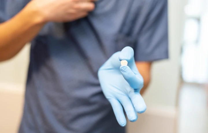 hisonrisa clinician holding one dental crown in a gloved hand in Mexico City.
