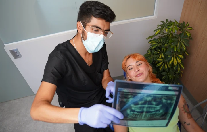 hisonrisa dentist reviewing a wisdom tooth x-ray with a patient in Roma Sur, Mexico City.